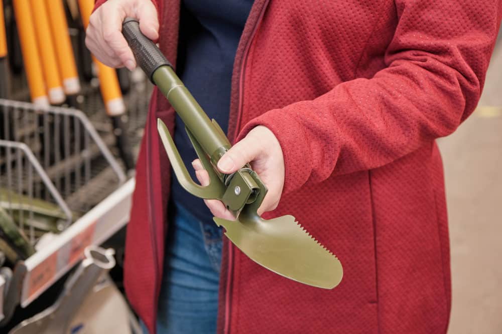 close up of man holding a folding shovel