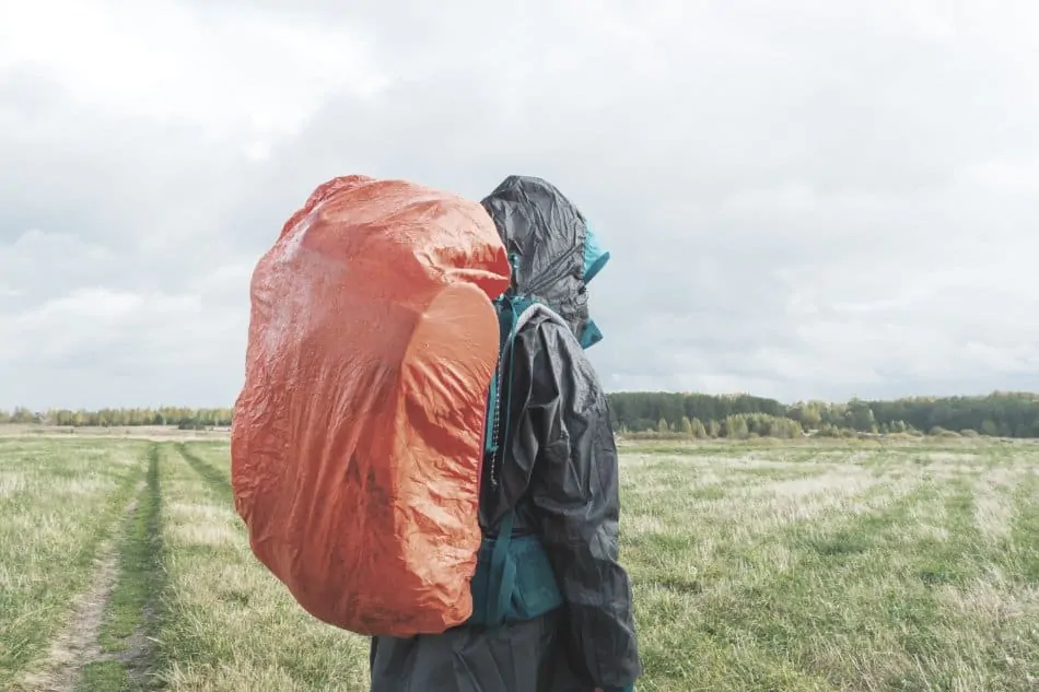 man wearing backpack in rain with rain cover