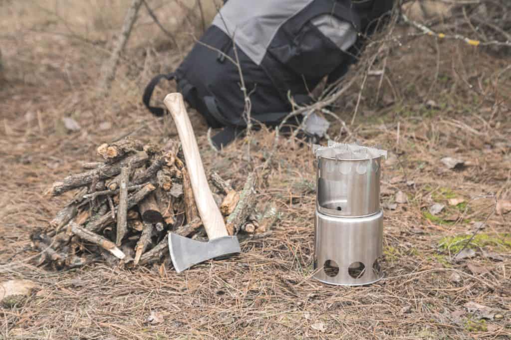 camping hatchet axe leaning on timber next to camp fire in woods