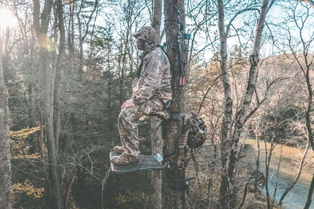a man standing patiently in a hunting treestand waiting for his prey