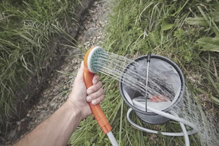 man holding portable water shower filling it with water for backpacking trip