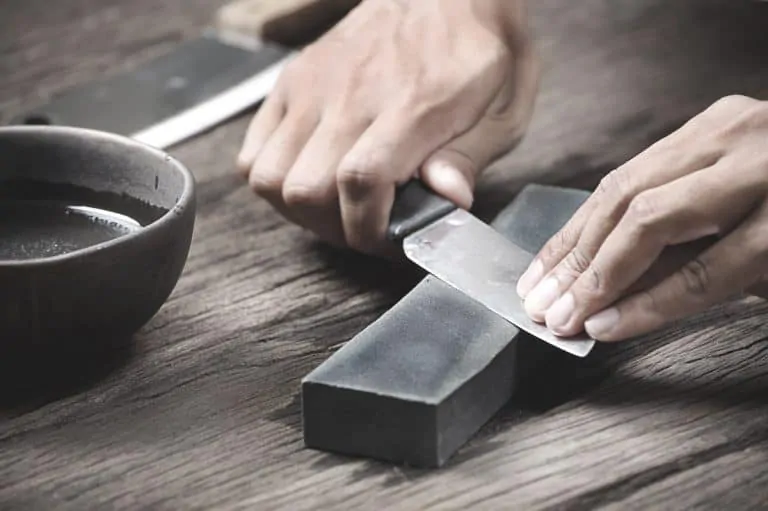 man sharpening knife with a sharpening stone