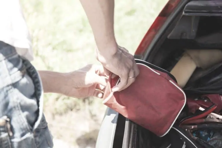 a man is placing a first aid kit in the trunk of his car