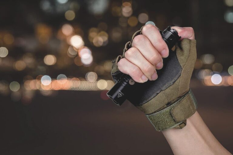 man wearing tactical glove holding the fenix pd36r tactical flashlight at night