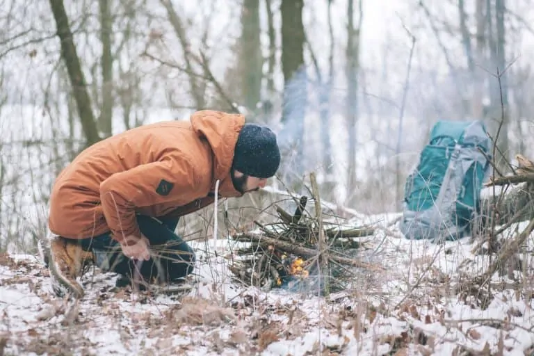 survivalist starting fire outdoors in winter