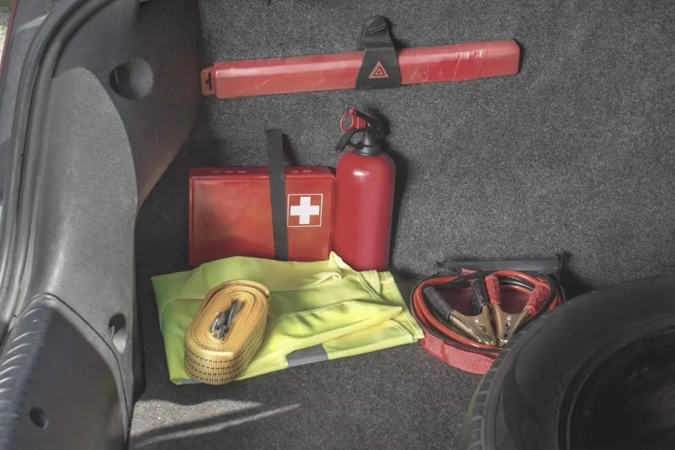 first aid kit located in trunk of car with fire extinguisher and jump leads