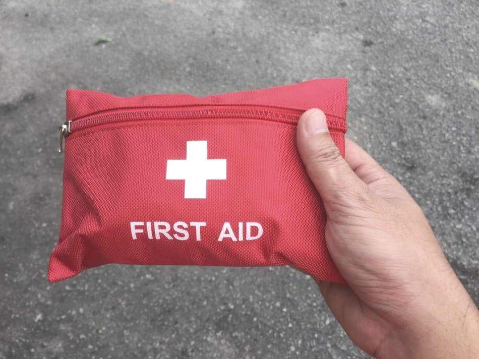 man holding small first aid kit in red pouch with white etxt