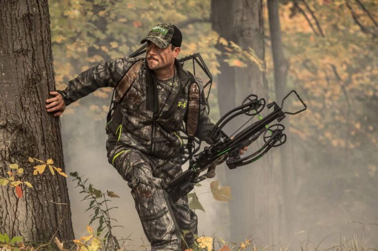 a man in the woods hunting holding a crossbow