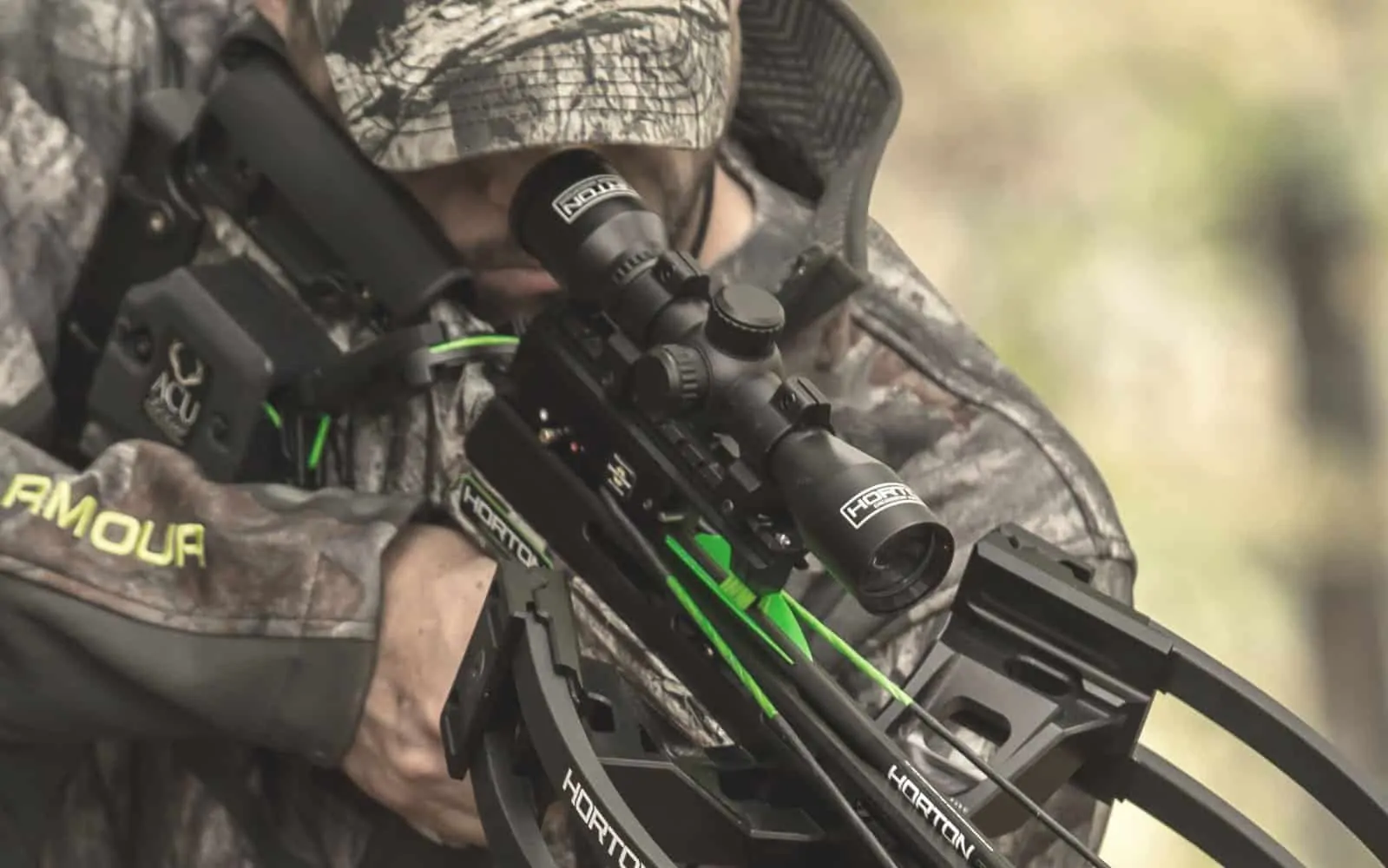 man looking through his scope on a crossbow in the woods