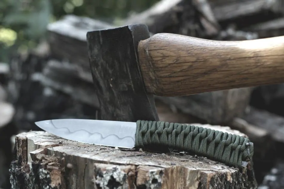 knife with a paracord handle resting on a tree stump in the woods