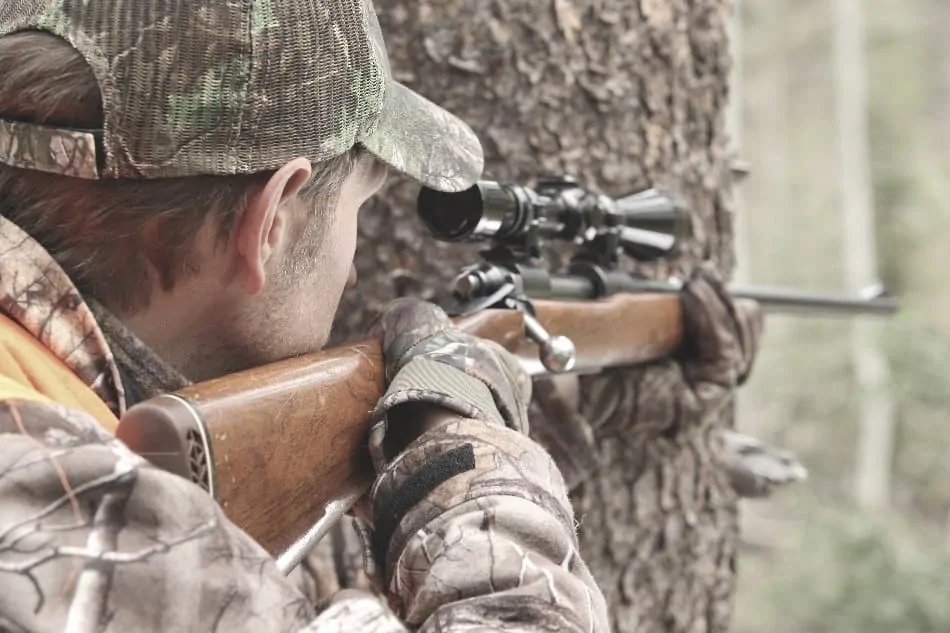 man taking aim with a hunting rifle