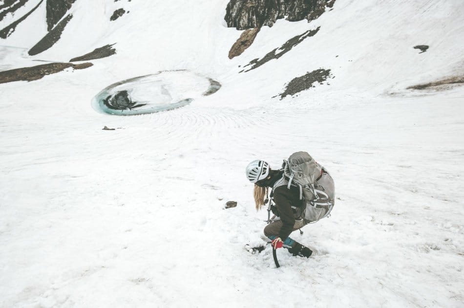 climbing woman with survival backpack in the snow