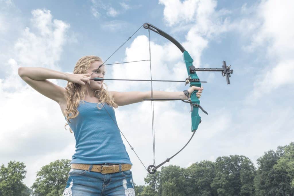 woman holding a beginner compound bow taking aim at her target