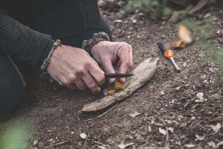 man in forest preparing tinder for lighting a fire