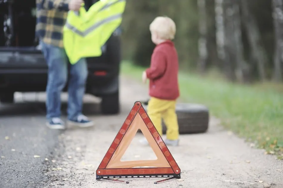 father puts safety vest on child after car breakdown emergency