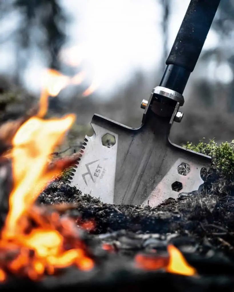 survival shovel being used to dig a hole for a fire pit