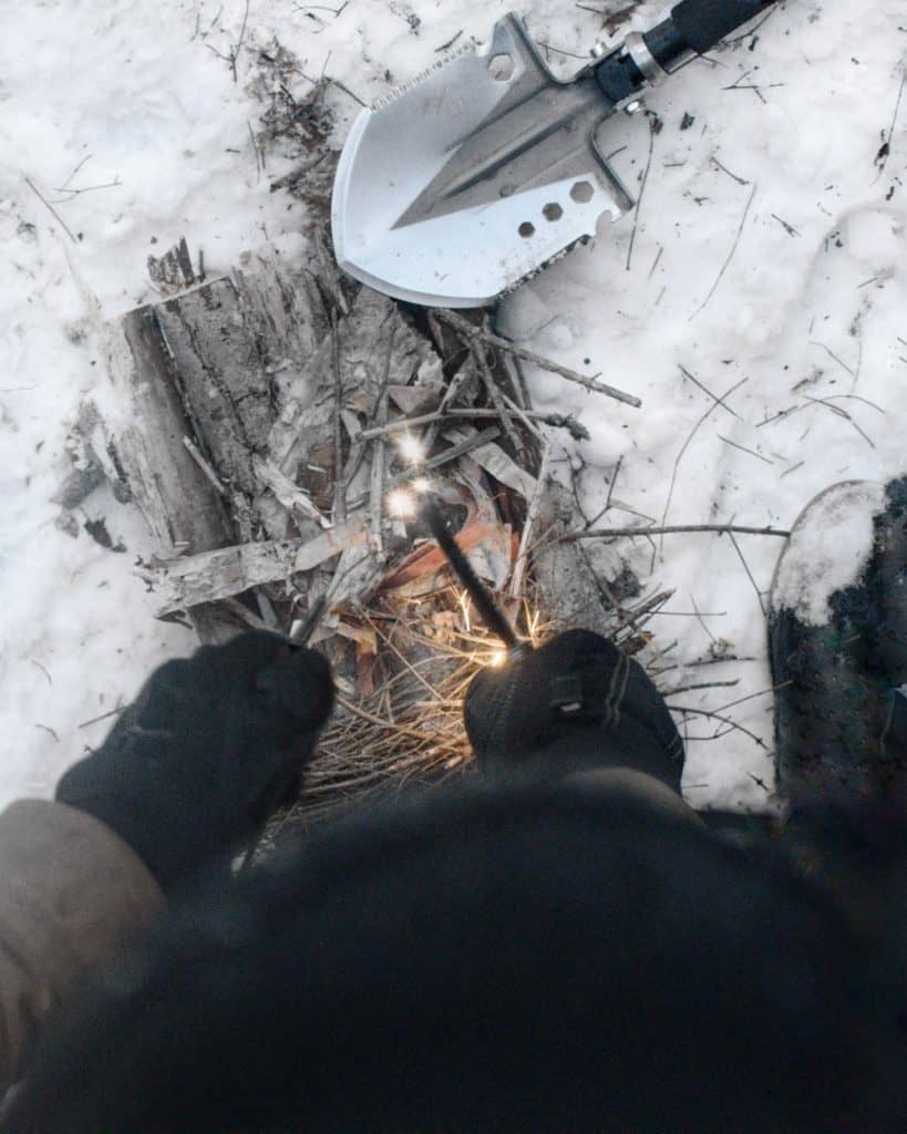 camper starting fire with fire rod from survival shovel handle