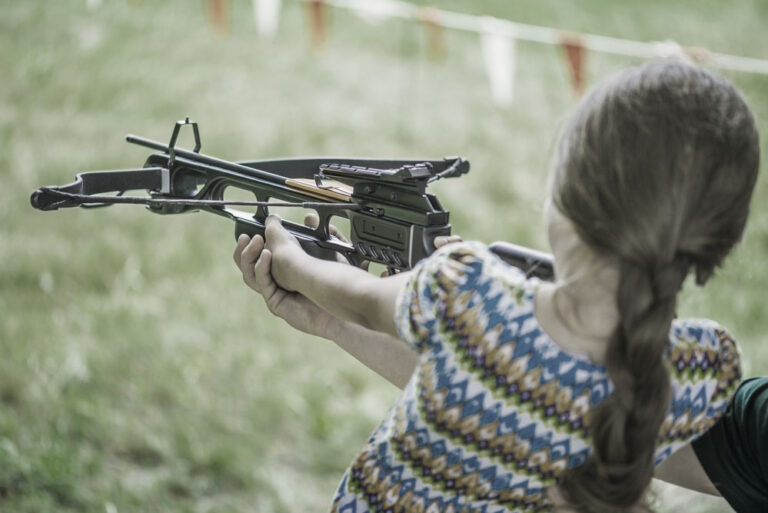 little girl learning to shoot a crossbow at the range