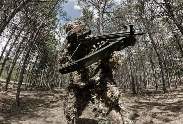 hunter in camoflage taking aim with a crossbow