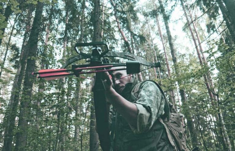 close up of hunter holding a crossbow taking aim in the woods