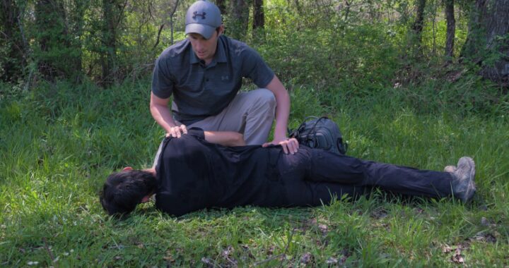 A Person Is Checking on An Injured Individual Lying on The Ground in The Woods